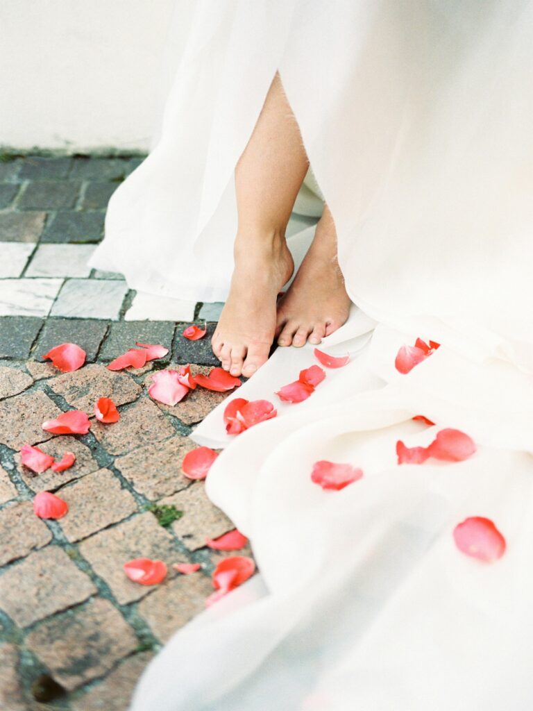 a woman in a white dress with rose petals on the ground