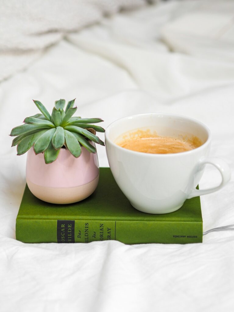 A cozy scene with a cup of coffee and a book on a bed.