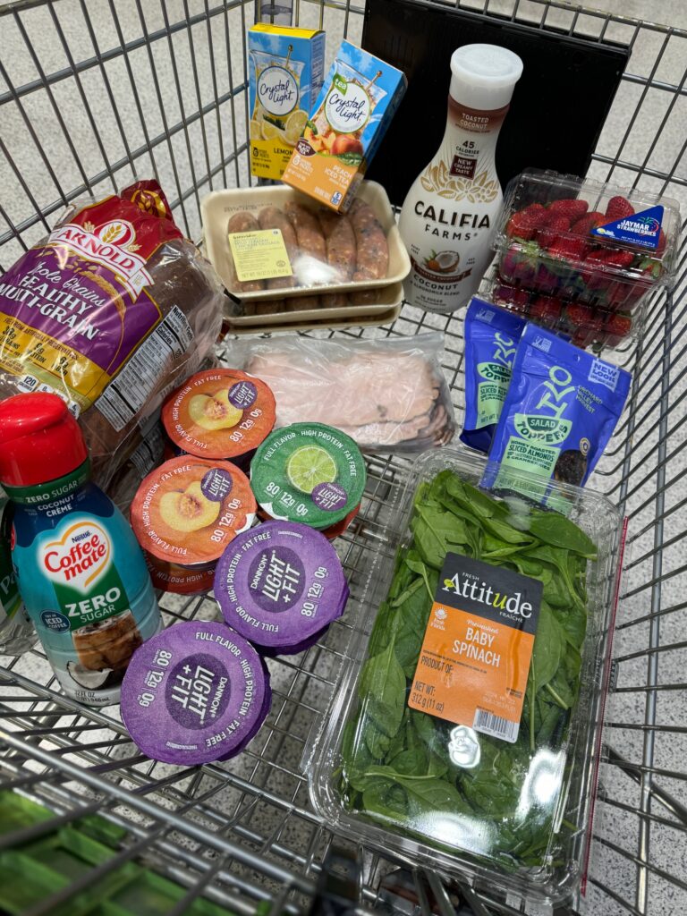 A full shopping cart with groceries including fruits, vegetables, bread, and dairy products.