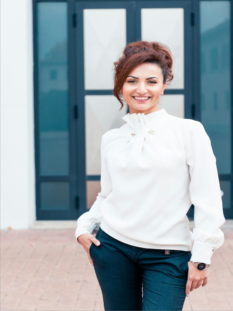 A woman in a white shirt and black pants standing confidently.