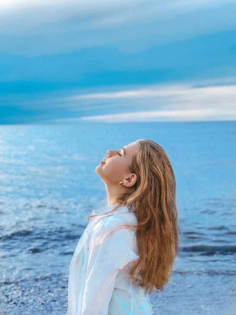 a woman standing on a beach looking up at the sky