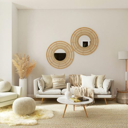 A cozy living room with a chic white sofa, two elegant round mirrors, and a stylish rug.