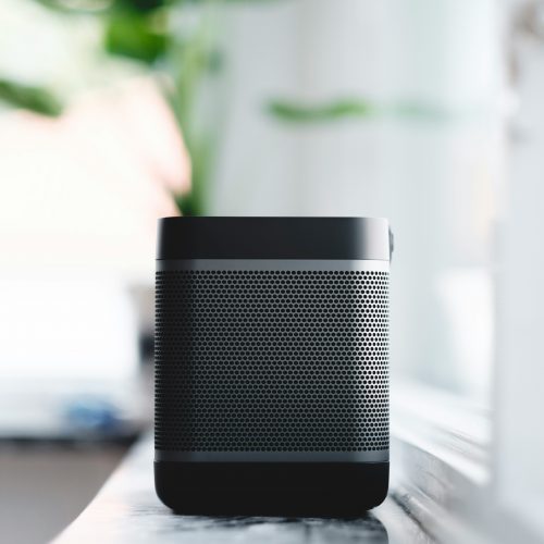 Black speaker placed on table next to window.