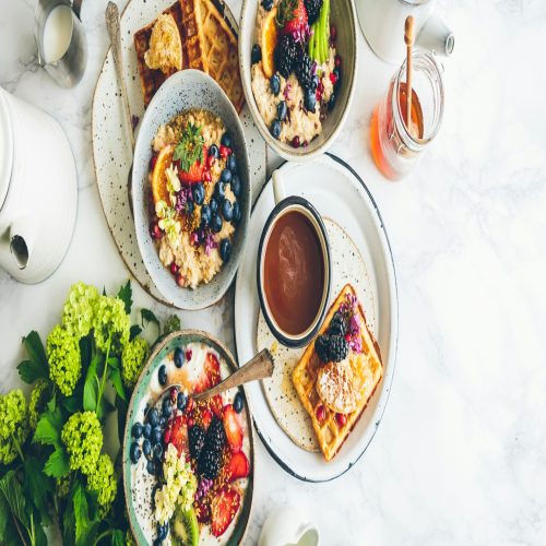 Breakfast spread with fresh fruit and golden waffles on a white marble table, a delightful start to the day.