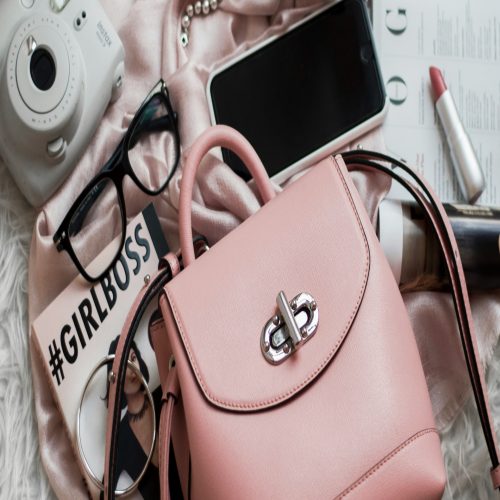 A collection of accessories including a pink purse, glasses, camera, and more.