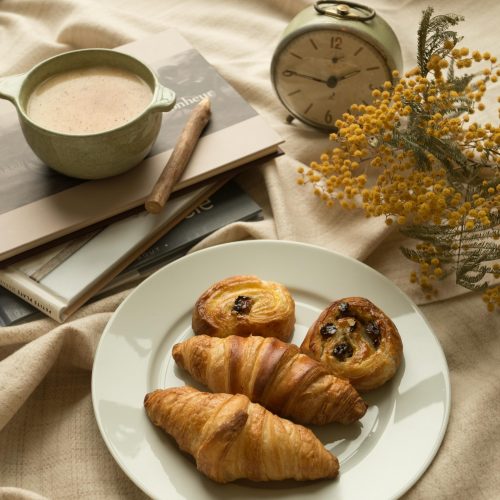 a white plate topped with croissants next to a cup of coffee