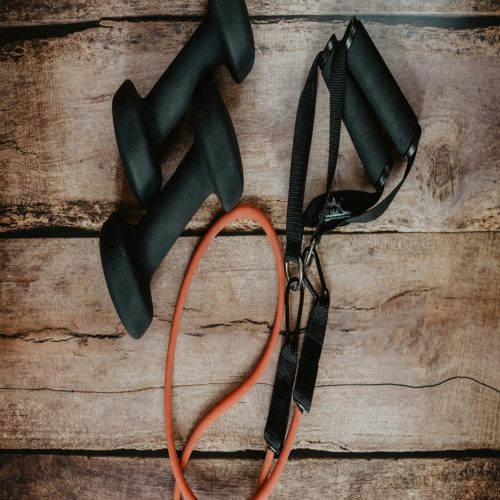 Dumbbells and rope on wooden floor, fitness equipment for strength training.