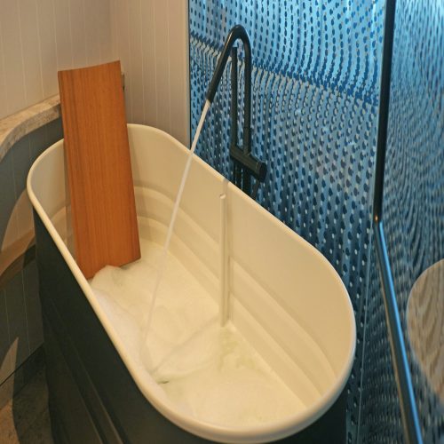 Relaxing bathtub with a wooden seat and faucet.