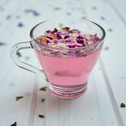 a glass cup filled with pink liquid and petals