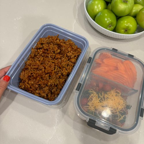 A person holding two containers of food, one next to the other.