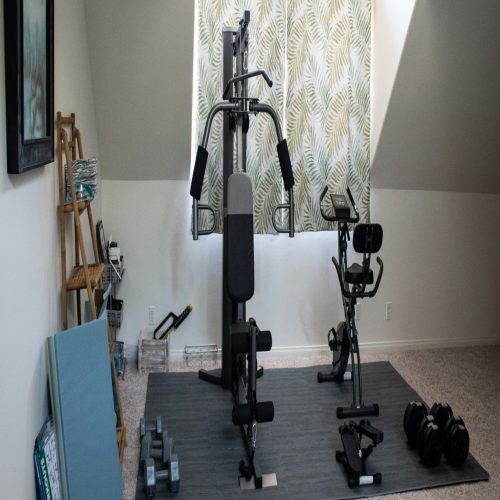 Home gym with weights, mat, and window.