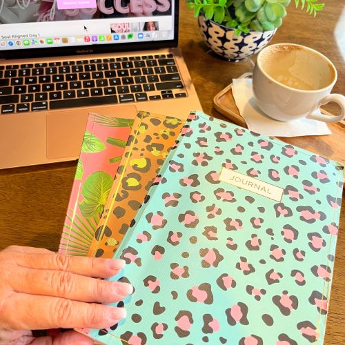 A leopard print notebook and a laptop side by side on a table.