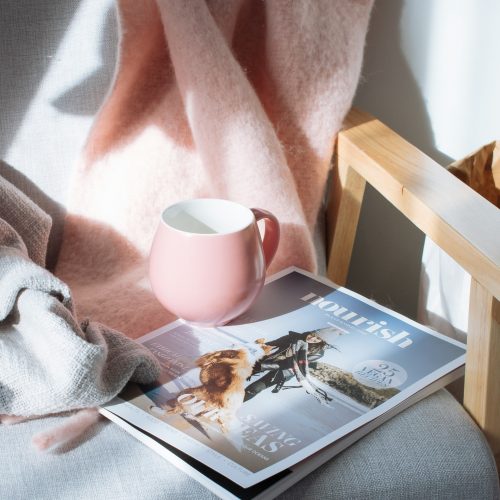 A magazine and a cup of coffee placed on a chair, creating a cozy and inviting atmosphere.