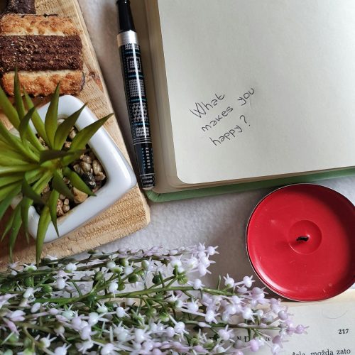 A table with a notebook, cake, and plant.