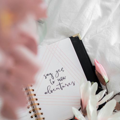 a notebook and flowers on a bed