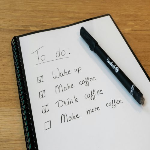 A notebook with a to-do list written on it, with a pen resting on top.