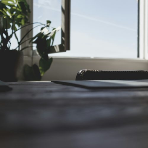 A laptop on a desk by an open window