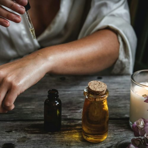 a person sitting at a table with a bottle of essential oils