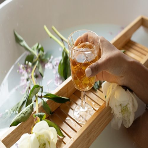 A person enjoying a glass of wine in a bathtub.