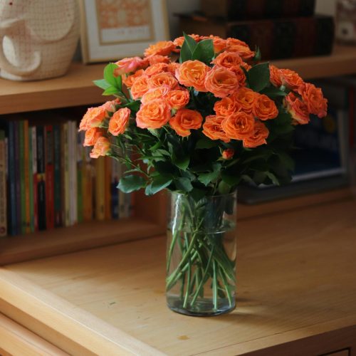 a vase filled with orange flowers on top of a wooden table