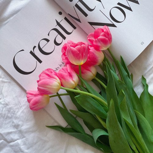 a bouquet of pink tulips sitting on top of a book