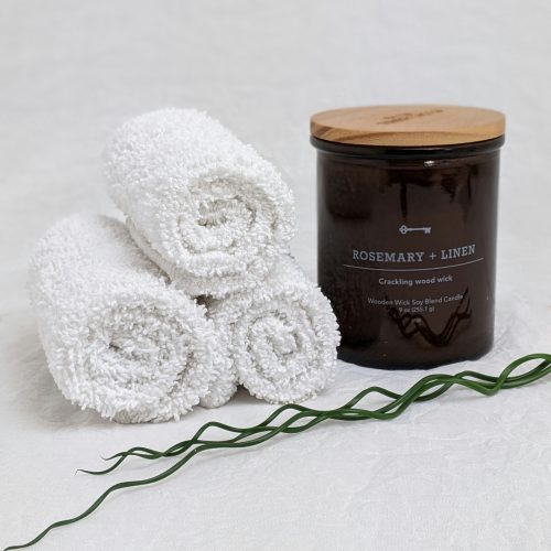 a jar of rosemary linen next to a pile of white towels