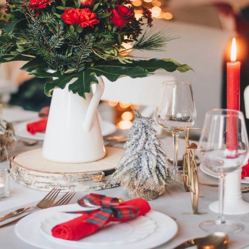 a table set for christmas dinner with a vase of flowers