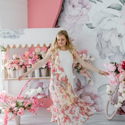 a woman dancing in front of a floral wallpaper