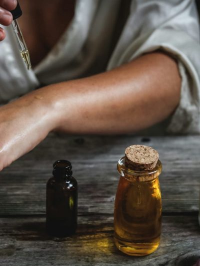 A woman holding a bottle of essential oils, showcasing the natural and aromatic properties of the product.