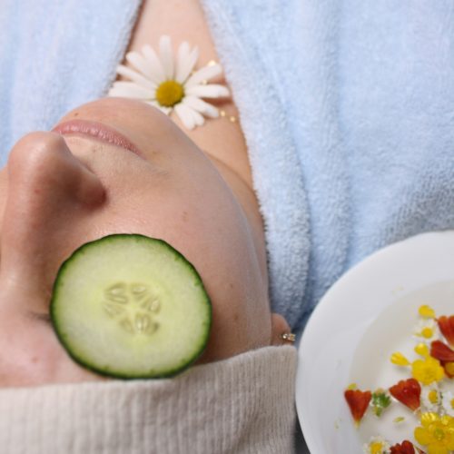 a woman laying down with a cucumber on her face