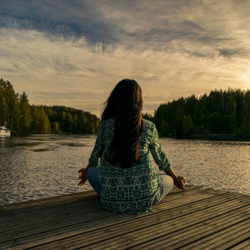 a woman sitting on a dock in front of a body of water