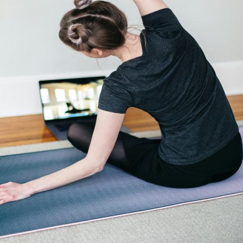 a woman sitting on a yoga mat stretching