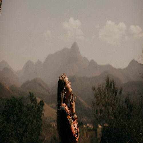 A woman standing in front of a mountain range.