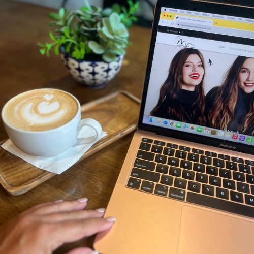 Image of a woman's hand using a laptop beside a coffee cup.